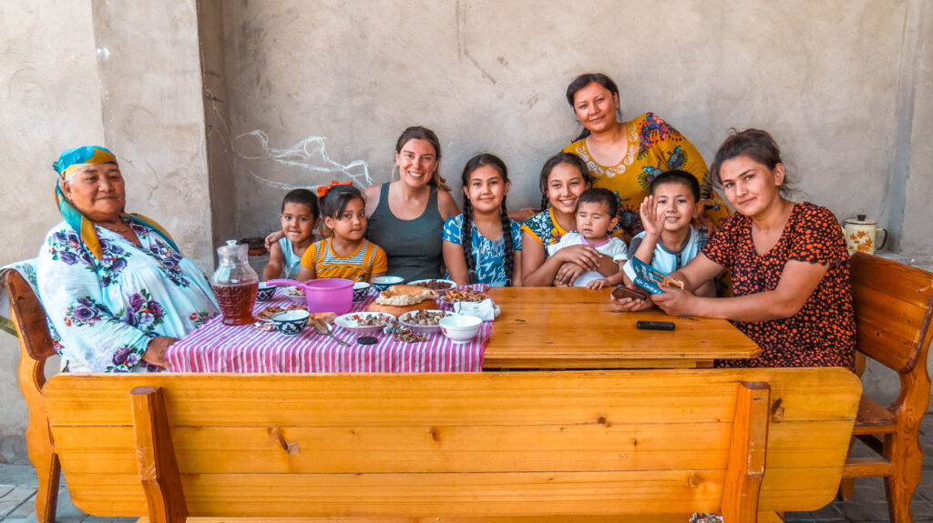 Flor with the family who hosted us in Shahrisabz, surrounded by children and in front of a hearty breakfast.
