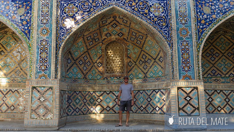 Juan en la Madrasa de Nodir Devon Begi de Bukhara, detrás una semi boveda de azulejos de colores.