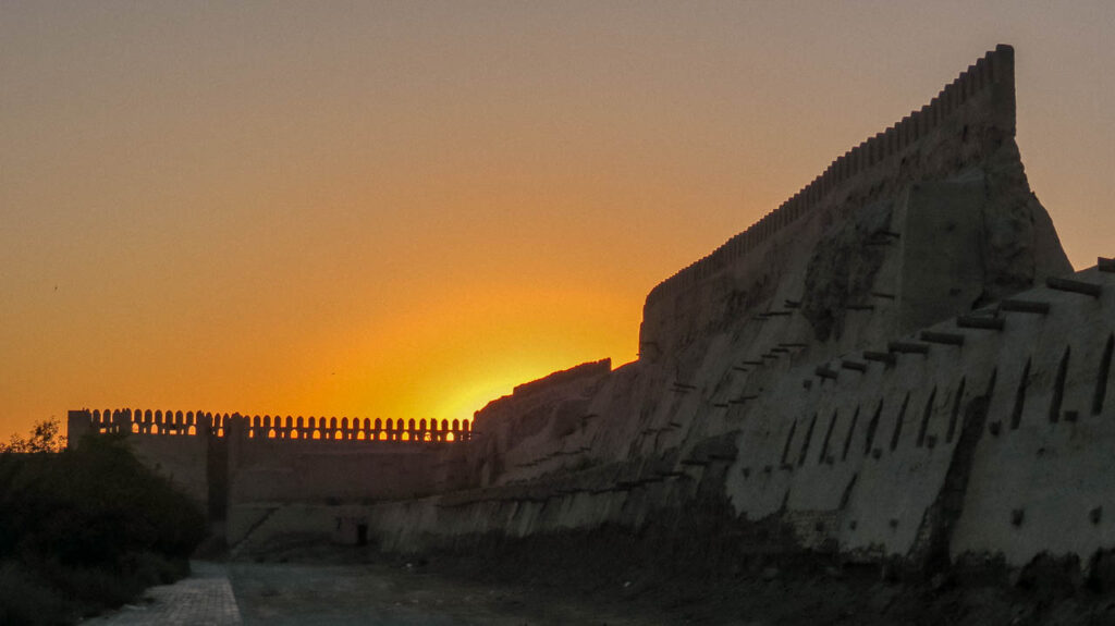 Las murallas de la ciudad de Bukhara al atardecer. El sol ya se puso detrás de ellas, aunque aún se puede ver el cielo anaranjado.
