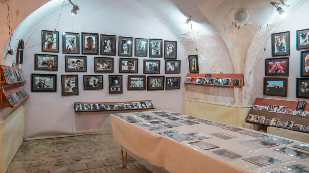 El interior de la Galería de Fotos de Bukhara que se presenta como una pequeña habitación con cuadros y fotografías en blanco y negro y a color sobre la pared.